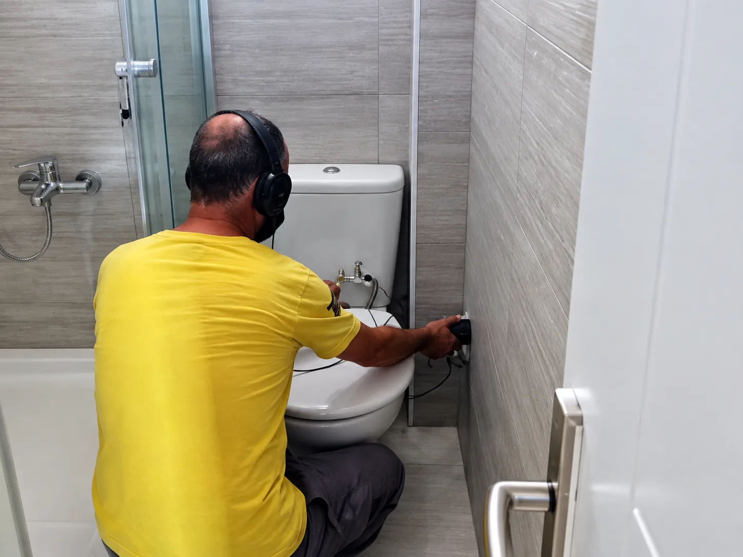 Banyoda tuvalet hattı çevresini akustik cihazla dinleyen teknisyen